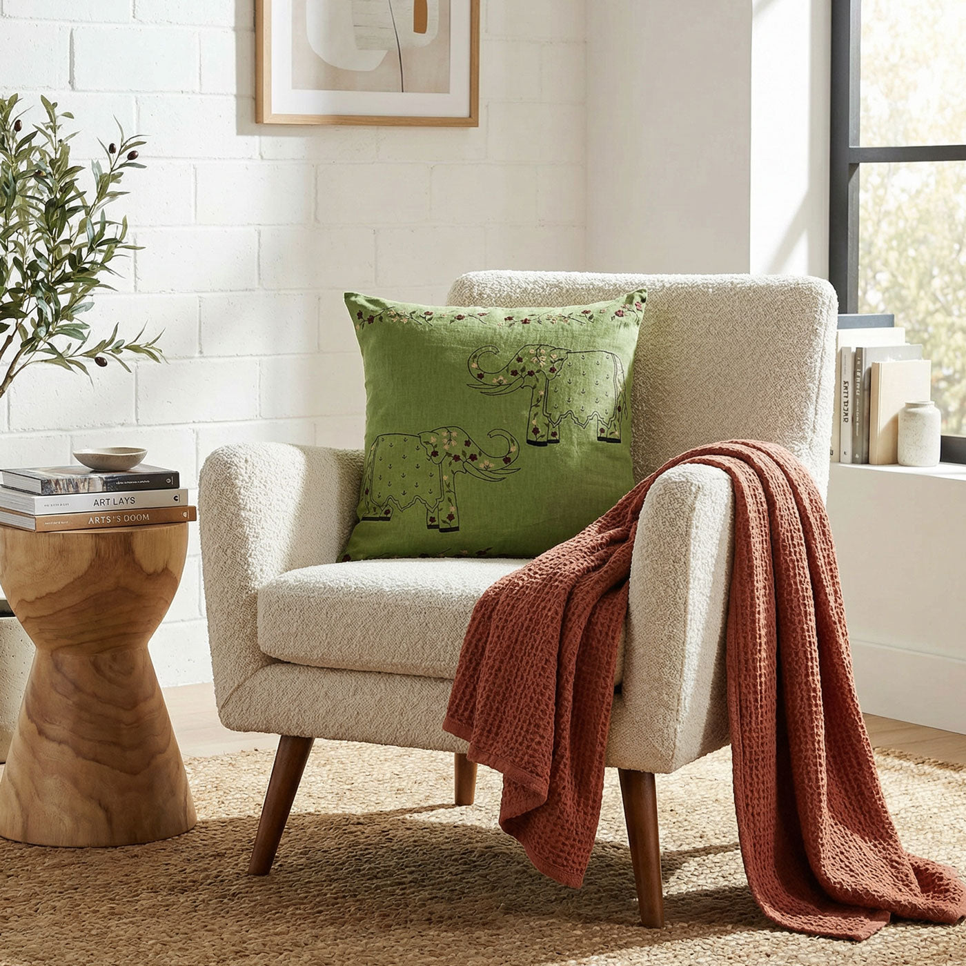 Beige armchair with a green pillow and red blanket in a cozy living room setting.