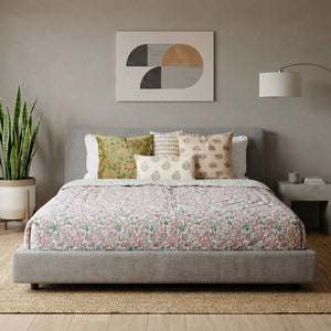 Bedroom with a bed featuring a floral quilt and patterned pillows, a plant, and abstract wall art.