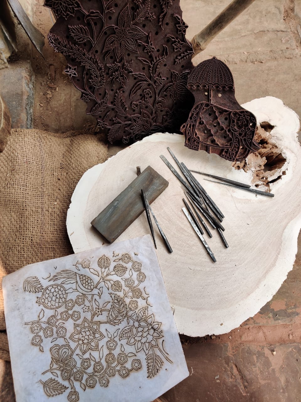 Carved wooden printing block being pressed onto fabric with a floral pattern