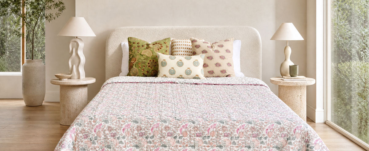 Foot of a bed with a pink and white floral block-printed quilt